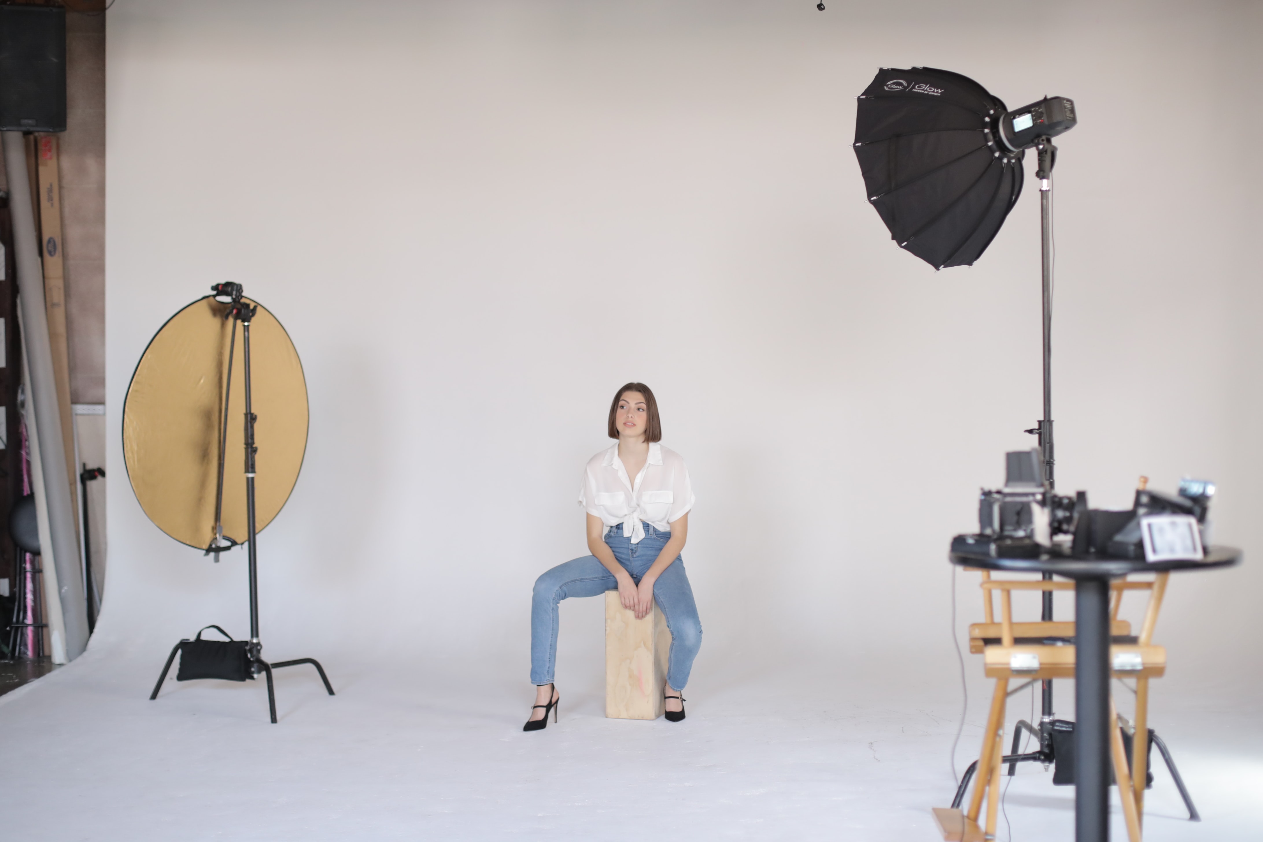 A studio setup with a camera on the left, a lighting prop on the right, and a model in the middle. Photo from Unsplash.com